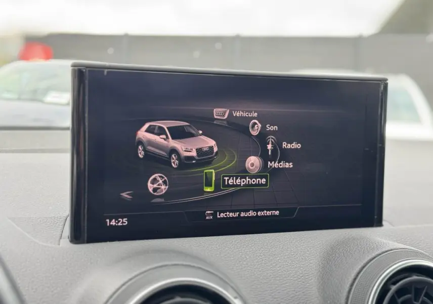 Écran central de l'Audi Q2 affichant le menu multimédia avec une miniature du SUV gris en vue 3/4 avant.