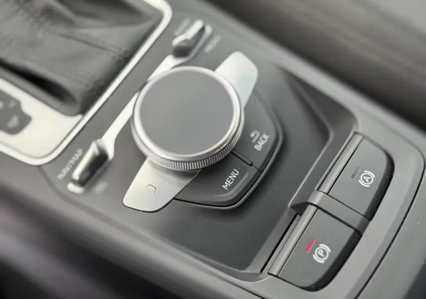 Gros plan sur la molette de commande MMI et les boutons de frein à main électrique dans l'intérieur noir de l'Audi Q2.