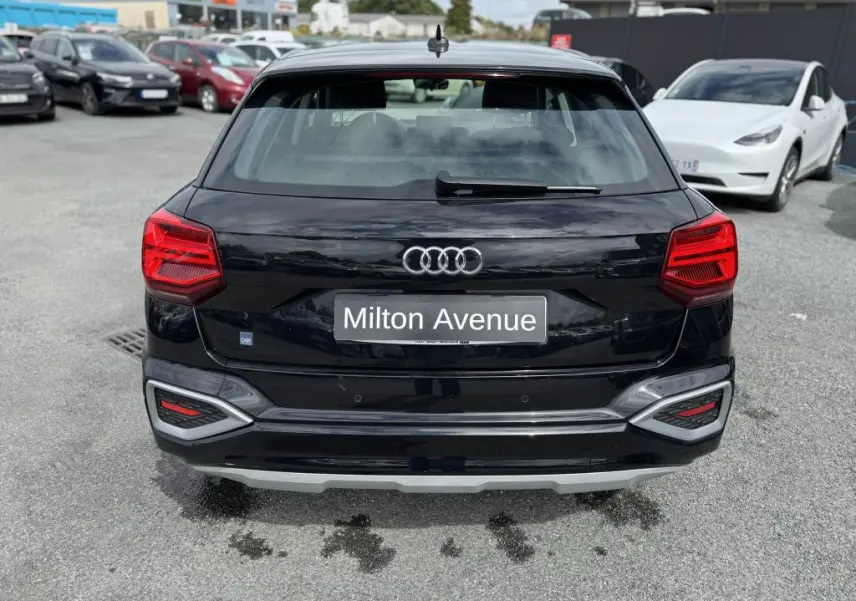 Vue arrière d'un Audi Q2 noir avec feux LED et logo Audi visible sur un parking.