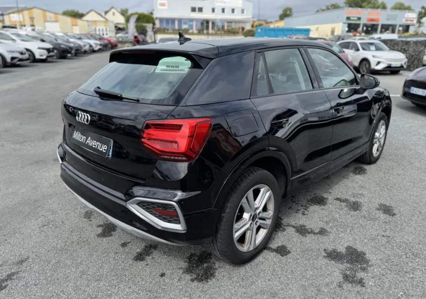 Audi Q2 noire vue en 3/4 arrière droit, avec feux arrière LED et jantes aluminium à 5 branches doubles.