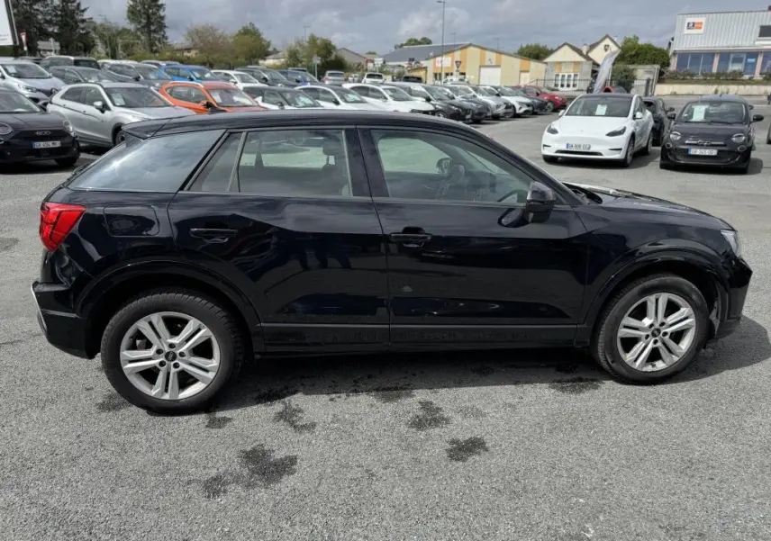 Audi Q2 noire vue de profil côté gauche, avec jantes aluminium 5 branches doubles et vitres teintées.