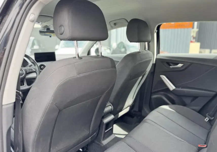 Vue intérieure arrière de l'Audi Q2 2022 noire, montrant les sièges tissu Skript et les appuie-têtes avant et arrière.