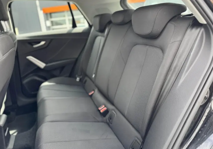 Vue intérieure côté droit des sièges arrière en tissu noir de l'Audi Q2 2022 avec ceintures et appuie-têtes intégrés.