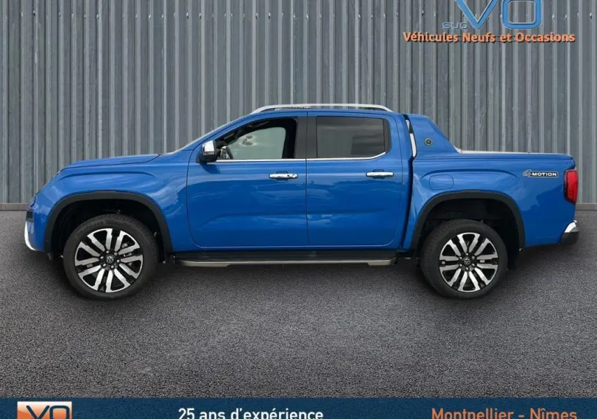 Profil côté gauche du pick-up Volkswagen Amarok Aventura bleu 2025 avec jantes alliage 21 pouces et marchepieds visibles.