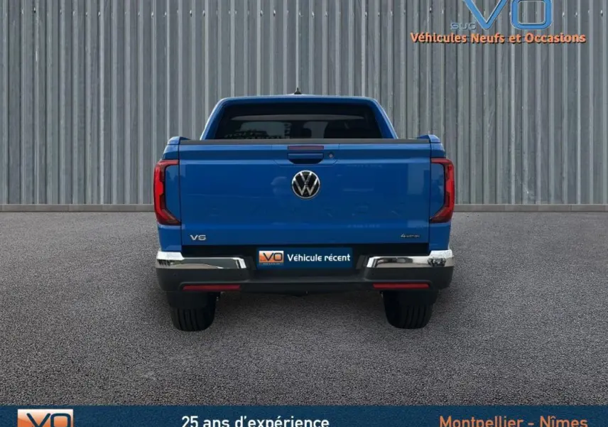 Vue arrière d'un Volkswagen Amarok Simple Cabine bleu 2025 avec logo VW et feux rouges verticaux visibles.