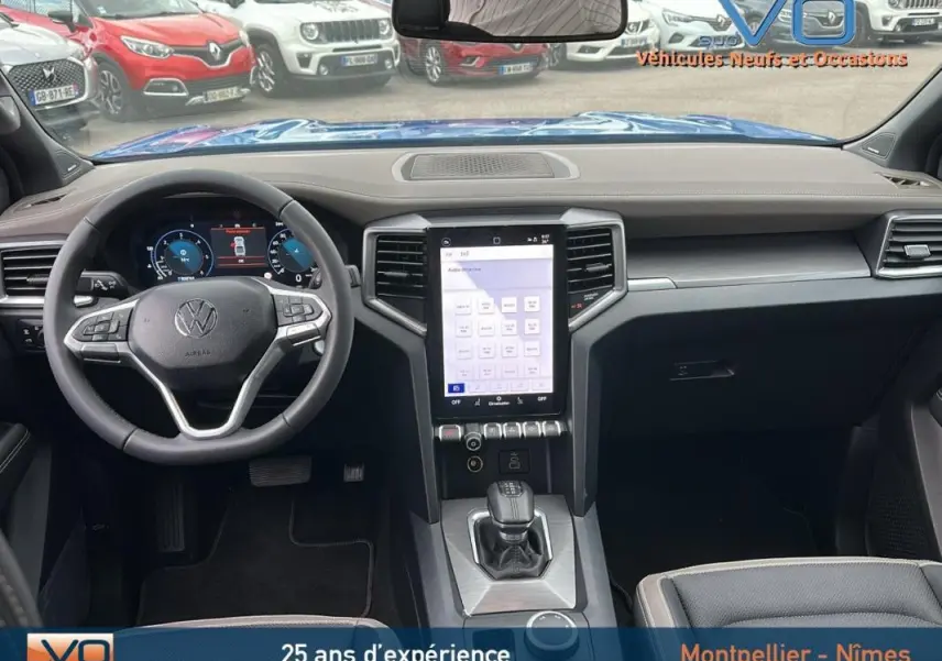 Intérieur du Volkswagen Amarok Simple Cabine 2025 bleu, vue frontale sur le tableau de bord avec écran tactile vertical et volant cuir.