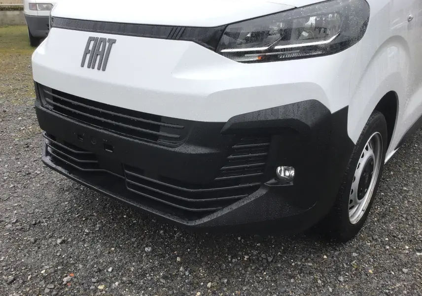 Vue 3/4 avant droit du FIAT Scudo Fourgon blanc 2024 avec pare-chocs noir et calandre marquée du logo FIAT.