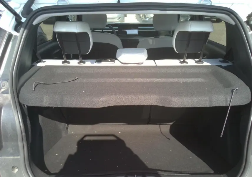 Coffre ouvert vu de l'arrière d'une Citroën C3 2025 noir Perla avec plage arrière et sièges blancs visibles.