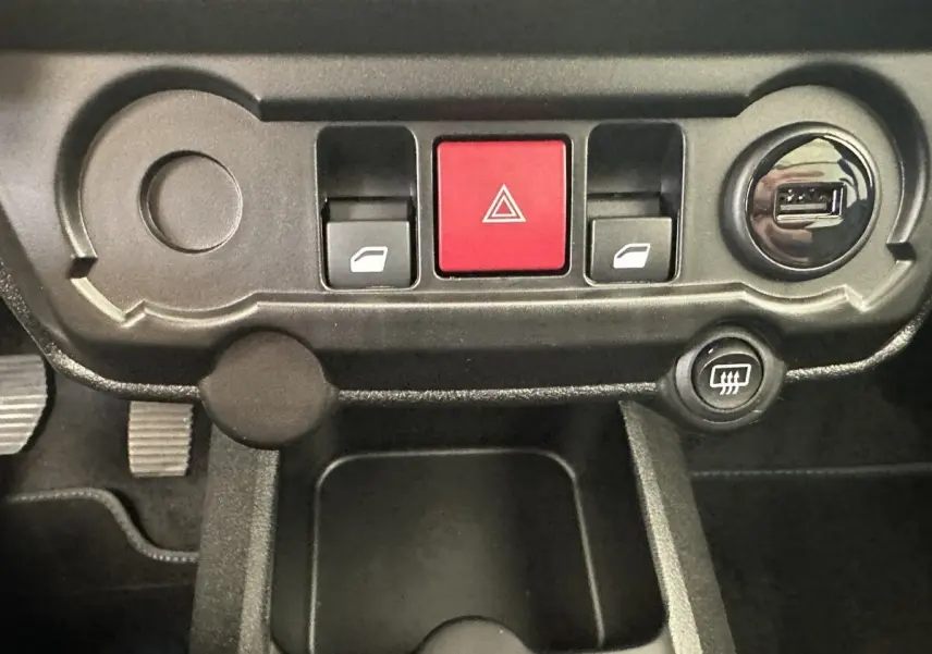 Vue rapprochée du tableau de bord noir de l'AIXAM AMBITION blanc, avec boutons de vitres, warning rouge et prise USB.