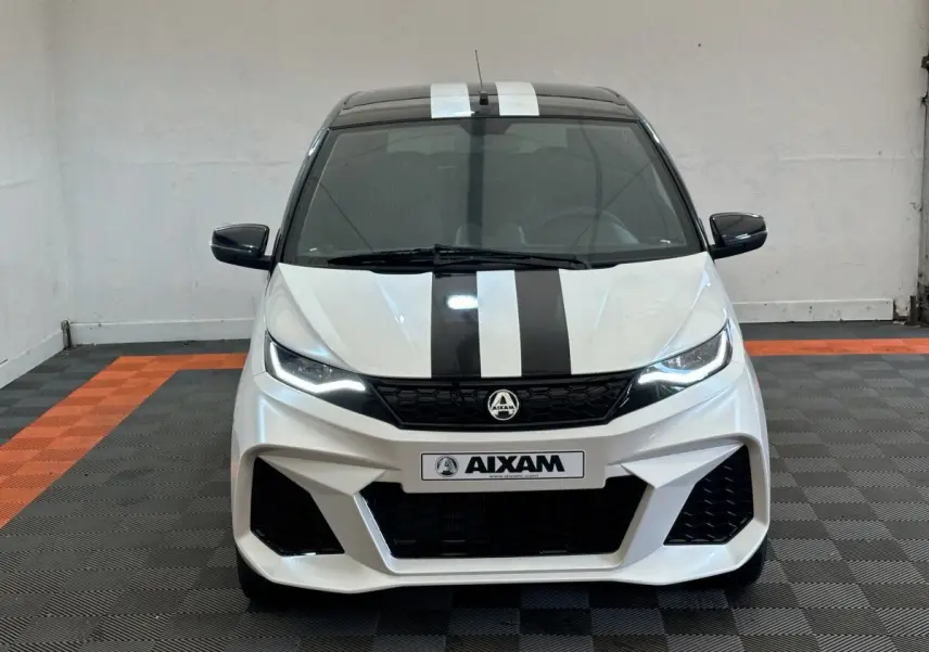 Vue avant d'une Aixam Ambition 0.5 City GTO blanche avec bandes noires et rétroviseur caméra côté gauche.