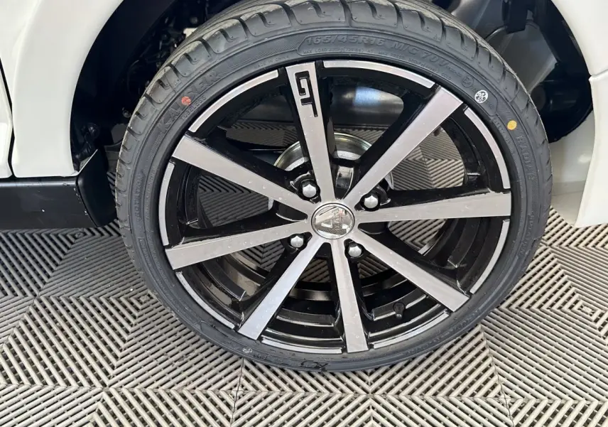 Gros plan sur la roue avant droite de l'AIXAM AMBITION 0.5 CITY GTO blanche, jante noire et argentée au design moderne.