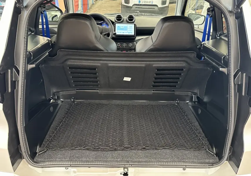 Vue arrière ouverte sur le coffre d'une Aixam Ambition 0.5 City GTO blanc, avec intérieur noir et sièges avant visibles.