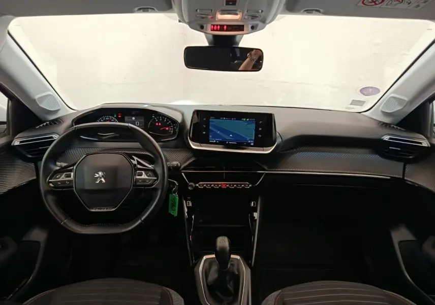 Vue intérieure avant de la Peugeot 208 blanche 2021, volant cuir multifonctions et écran tactile de navigation central.