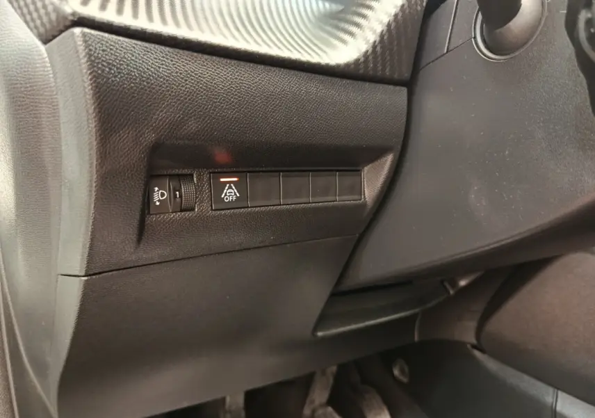 Détail intérieur côté gauche du tableau de bord noir avec commande réglage hauteur phares et désactivation assistance au maintien de voie.