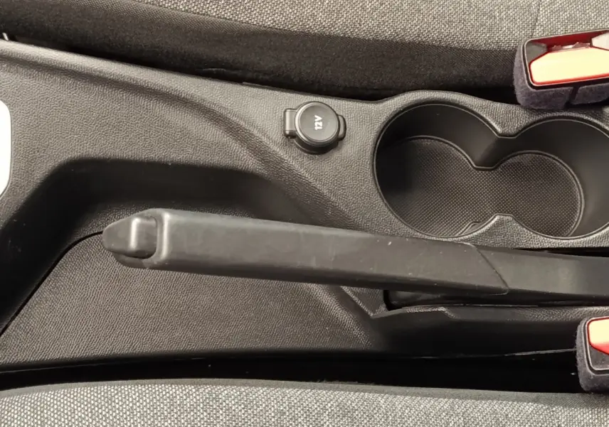 Le frein à main manuel et prise 12V visibles entre les sièges avant d'une Peugeot 208 blanche.