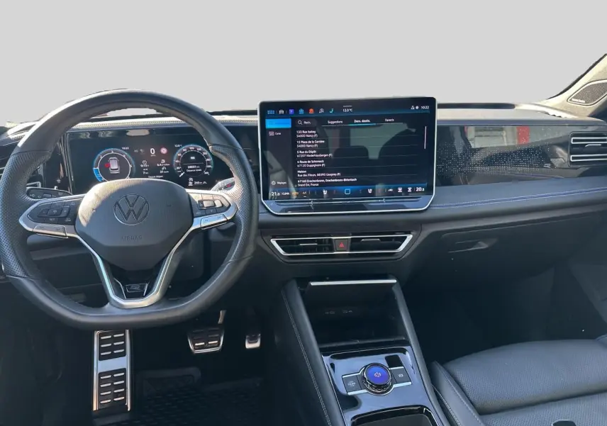 Vue intérieure frontale du Volkswagen Tiguan 2024, tableau de bord noir avec écran tactile central et volant multifonction cuir.