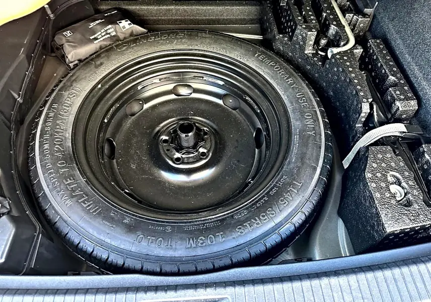 Gros plan sur la roue de secours noire dans le coffre du Volkswagen Tiguan gris dauphin 2024.