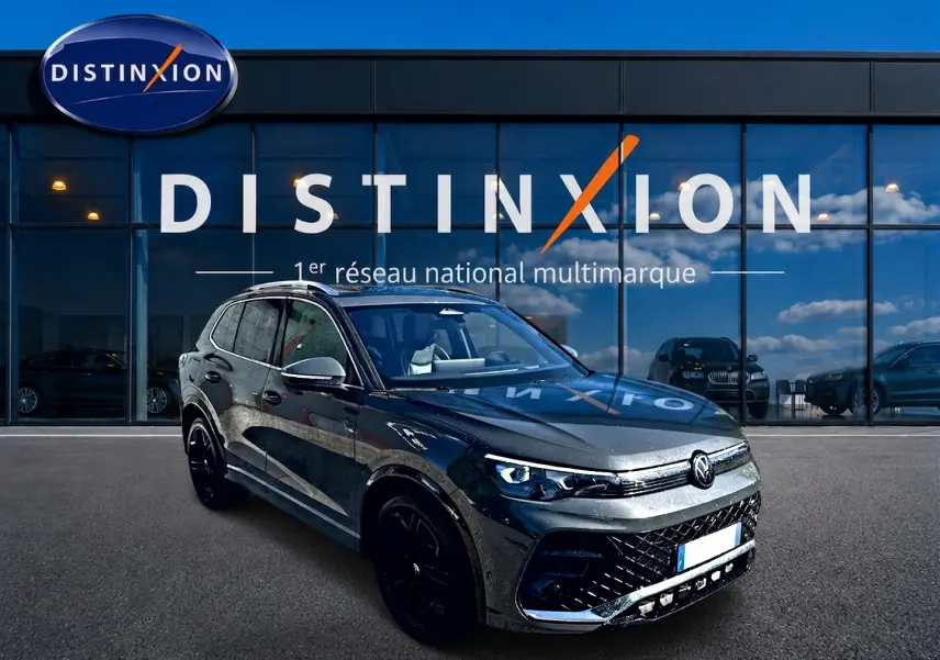 Volkswagen Tiguan gris dauphin en 3/4 avant droit, avec jantes noires et calandre R-Line distinctive.