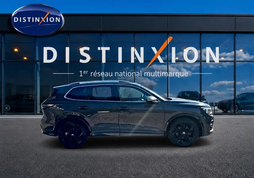 Volkswagen Tiguan 2.0 TDI 150 R-Line gris dauphin vu de profil côté gauche devant une vitrine Distinxion.