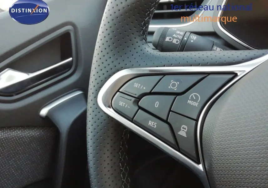 Gros plan sur les commandes à gauche du volant perforé d’un Renault Captur noir étoile métal, intérieur gris-noir.