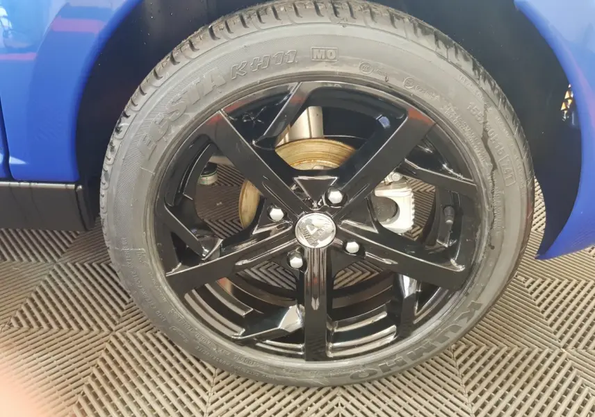 Gros plan sur la roue avant droite noire brillante d'une Aixam Ambition 0.5 City Sport bleu 2026.