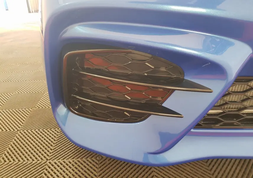 Gros plan sur la calandre avant droite bleu métallisé de l'AIXAM AMBITION 0.5 CITY SPORT avec grille noire alvéolée.