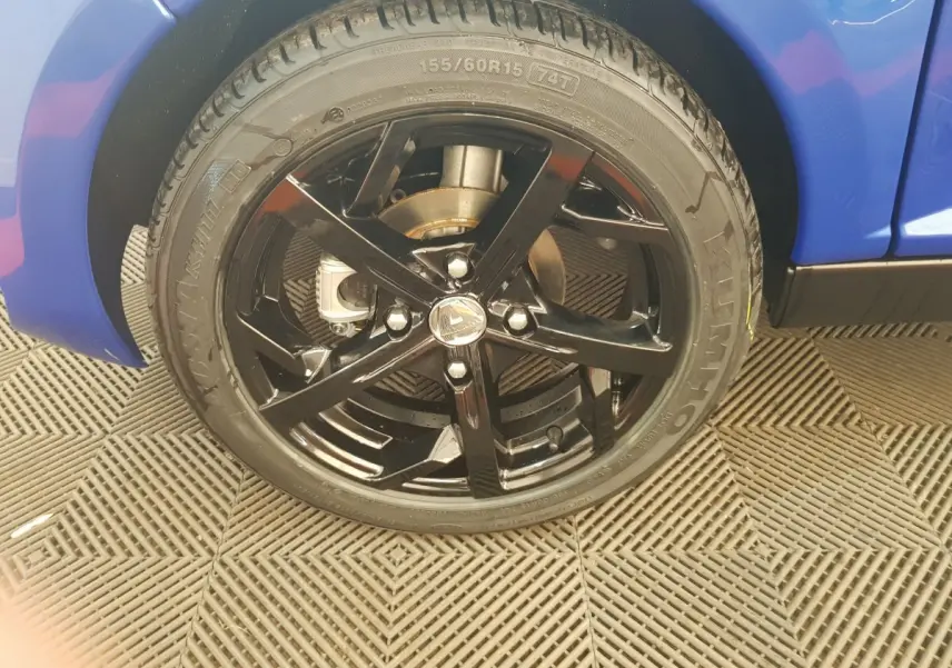 Gros plan sur la roue avant droite noire brillante d'une Aixam Ambition 0.5 City Sport bleu 2026.