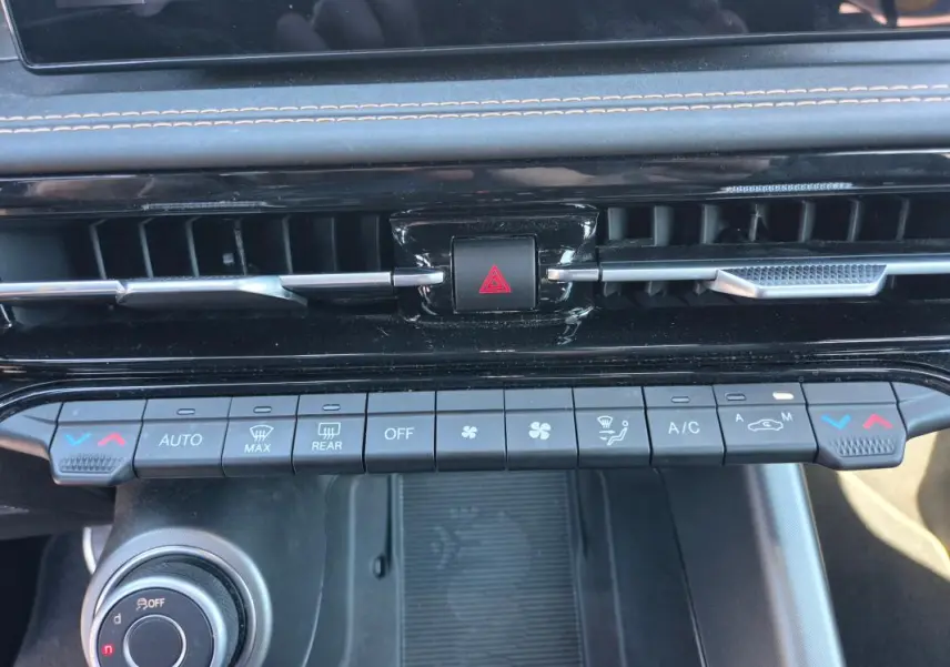 Tableau de bord de l'Alfa Romeo Tonale 2025, vue rapprochée des commandes de climatisation et ventilation noires.