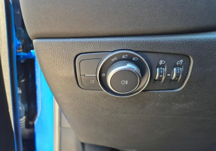 Gros plan sur les commandes d’éclairage intérieures d’une Alfa Romeo Tonale bleu, avec molette et réglages lumineux.