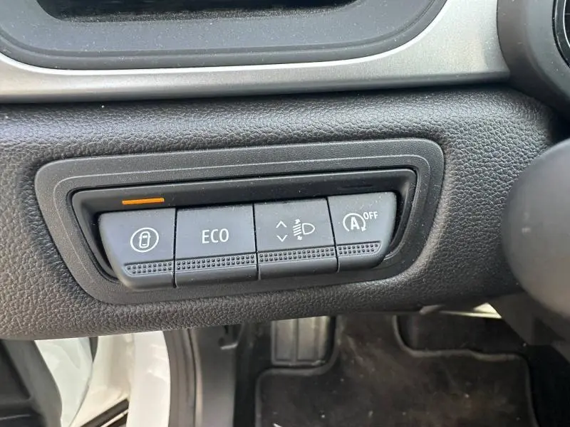 Gros plan sur les boutons de commande du mode ECO et du verrouillage central dans un Renault Captur blanc nacré 2025.