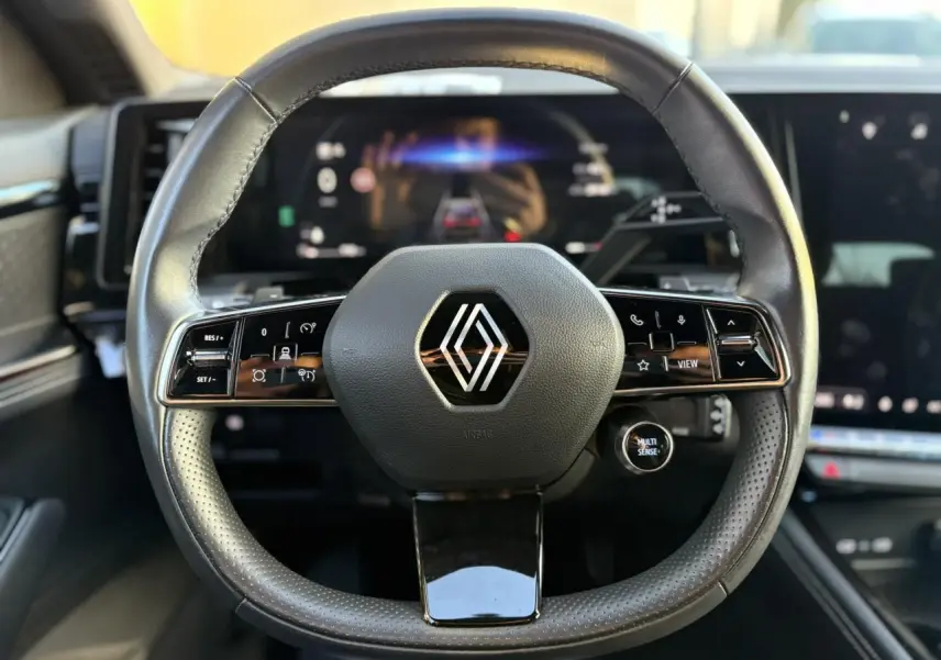 Volant cuir noir perforé Renault Australe 2023 avec commandes intégrées et tableau de bord numérique en arrière-plan