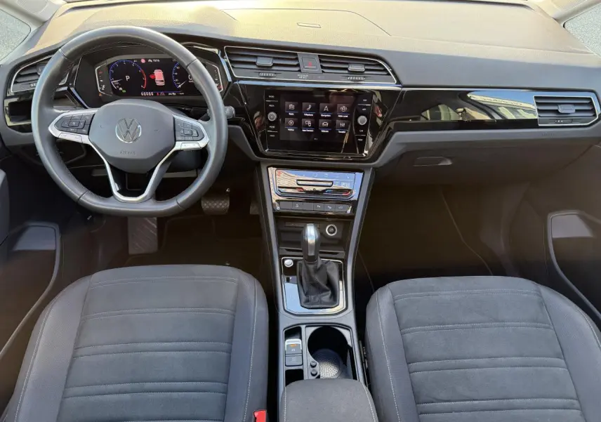 Vue intérieure frontale du tableau de bord et volant cuir multifonction du Volkswagen Touran 2025 en microfleece gris.
