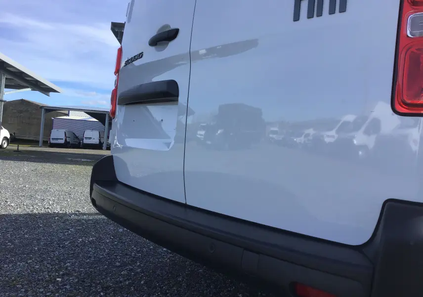 Vue rapprochée arrière gauche du fourgon blanc FIAT Scudo XL 2024 avec pare-chocs noir et logo visible.