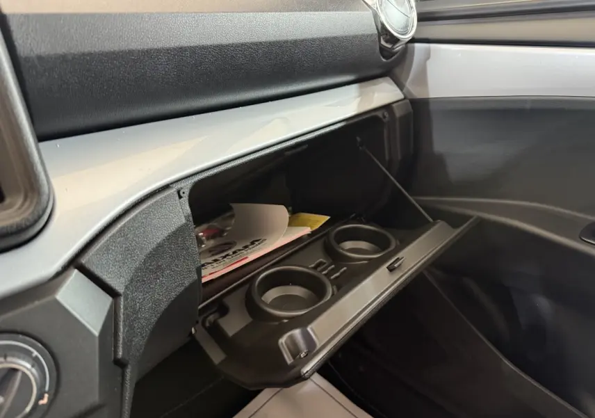 Intérieur côté passager de l'AIXAM Ambition 0.5 Crossover Premium 2026 gris foncé, boîte à gants ouverte avec porte-gobelets.