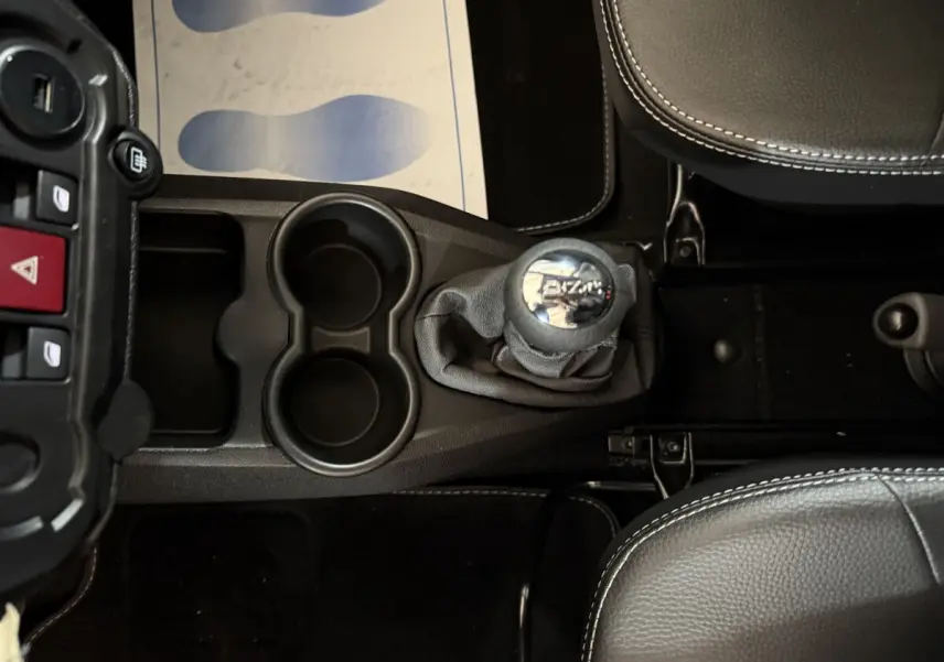 Vue plongeante sur la console centrale de l'AIXAM AMBITION 0.5 CROSSOVER PREMIUM avec levier de vitesse et porte-gobelets noirs.