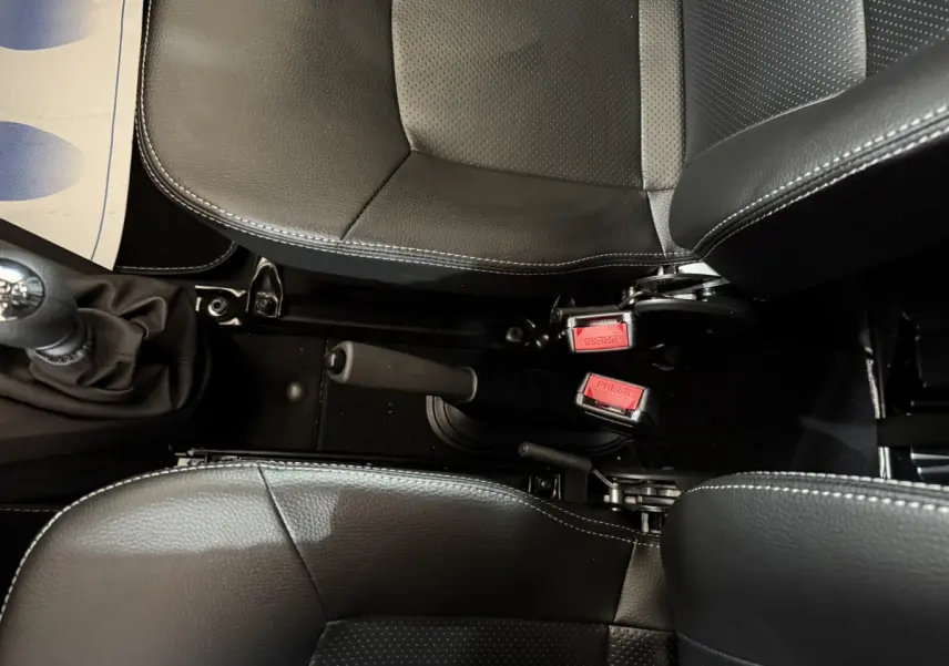 Vue plongeante sur les sièges noirs et la console centrale avec frein à main et ceintures rouges d'une Aixam Ambition 0.5 Crossover Premium.