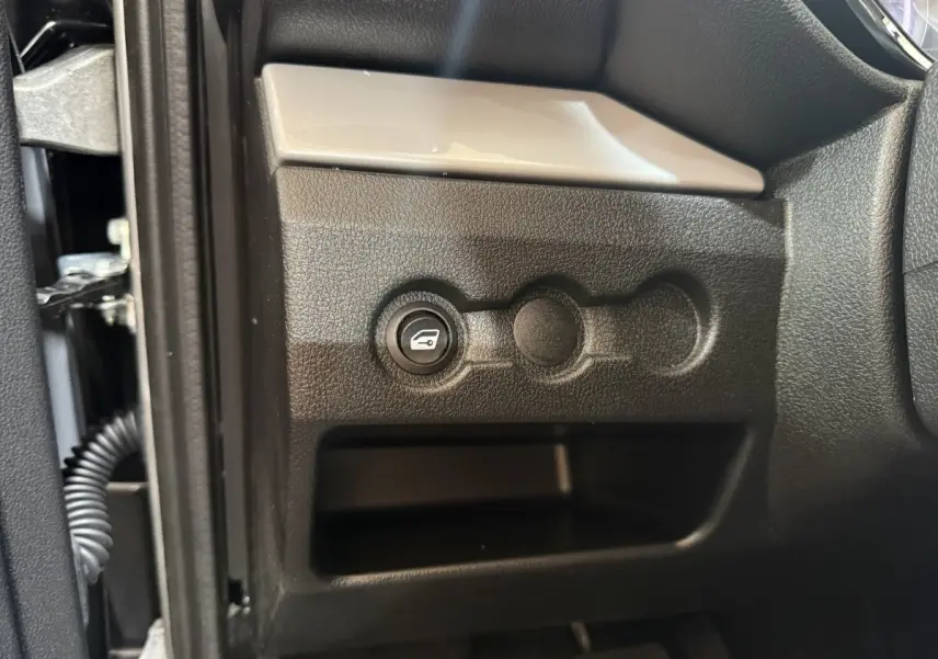 Gros plan sur le bouton d'ouverture du coffre côté conducteur dans l'habitacle de l'AIXAM AMBITION 0.5 CROSSOVER PREMIUM 2026.