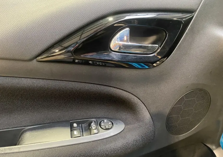 Gros plan sur la poignée intérieure et les commandes de porte côté conducteur d'une Citroën DS3 noire.