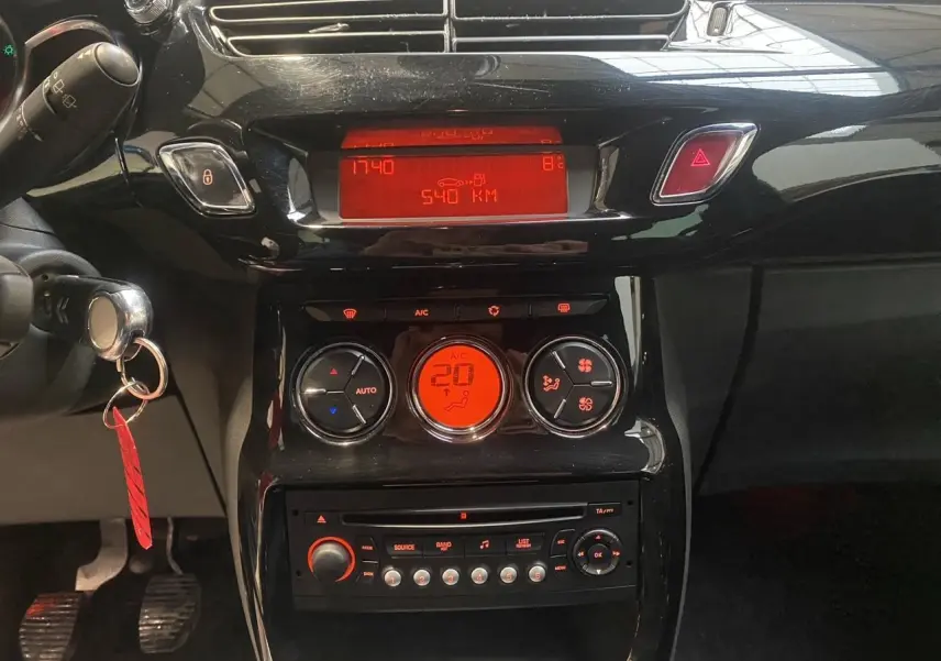 Vue rapprochée du tableau de bord noir de la Citroën DS3 2011, avec affichage digital rouge et commandes climatisation.