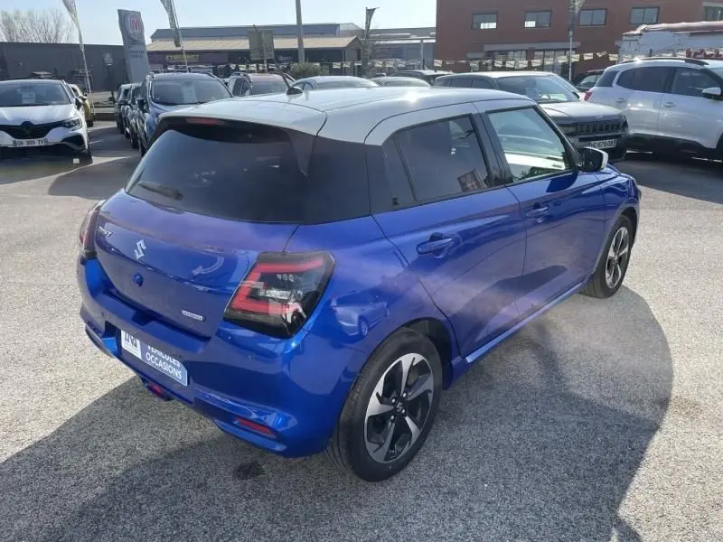 Vue 3/4 arrière droite d'une Suzuki Swift 2024 bleu métal avec toit blanc et jantes alliage distinctives.