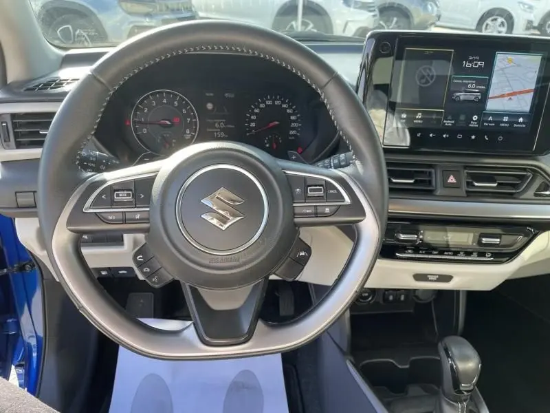 Vue intérieure centrée sur le volant et le tableau de bord d'une Suzuki Swift bleu métal 2024 avec écran tactile et commandes au volant.