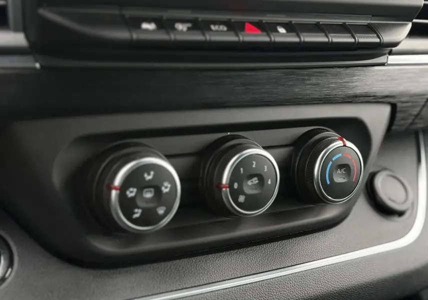 Gros plan sur les commandes de climatisation du tableau de bord du Nissan Primastar Combi noir métal 2025.