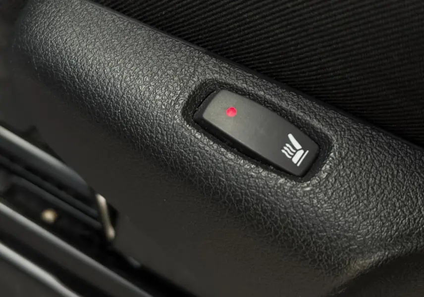 Gros plan sur le bouton de siège chauffant noir dans l'habitacle du Nissan Primastar Combi noir métal 2025