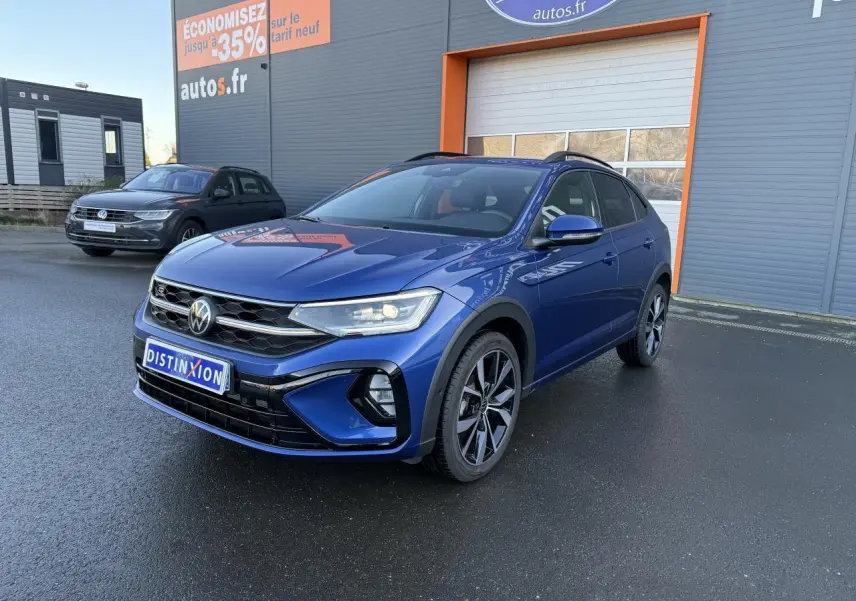 Volkswagen Taigo bleu récif métallisé en 3/4 avant droit avec jantes alliage noires brillantes sur parking.