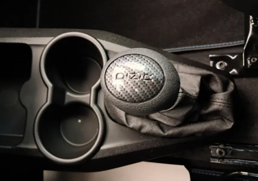 Gros plan sur le levier de vitesses DIZAL en carbone et les porte-gobelets noirs de l'AIXAM AMBITION 0.5 CITY COUPE GTI blanc.