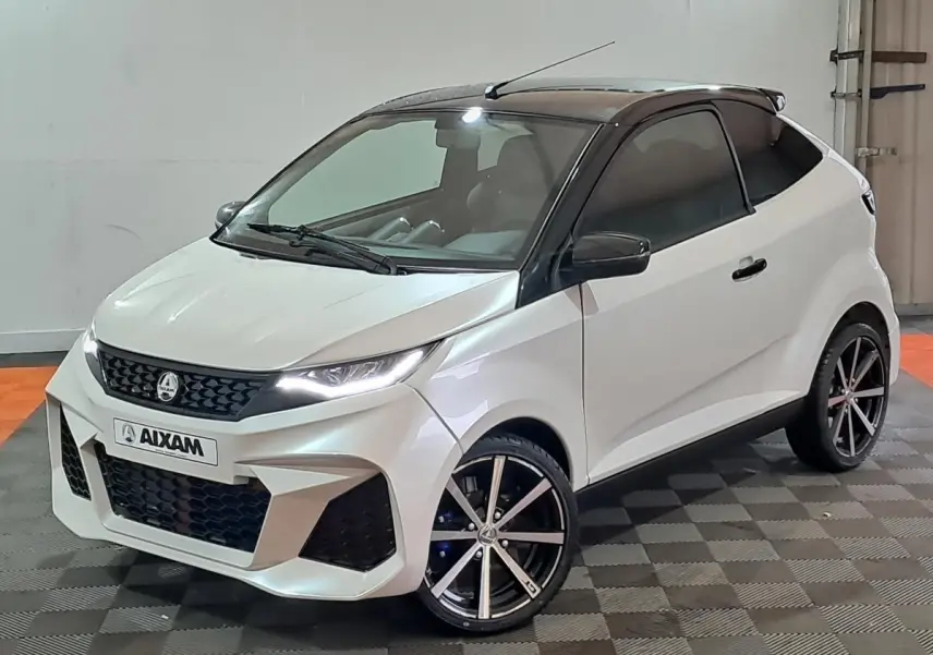 Vue 3/4 avant droite de l'AIXAM AMBITION 0.5 CITY COUPE GTI blanc avec toit noir et jantes sport noires.