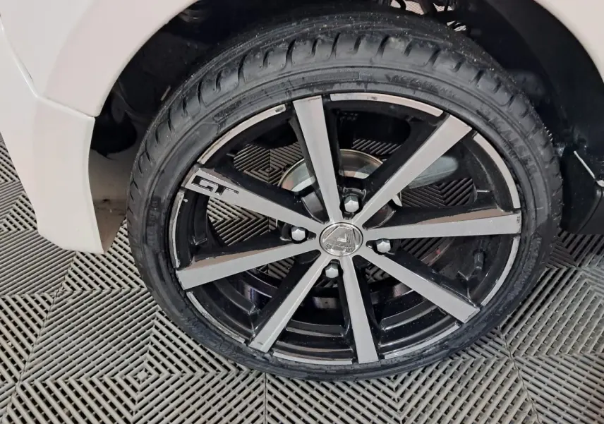 Gros plan sur la roue avant droite noire et argentée avec logo GT d'une Aixam Ambition blanche 2026.