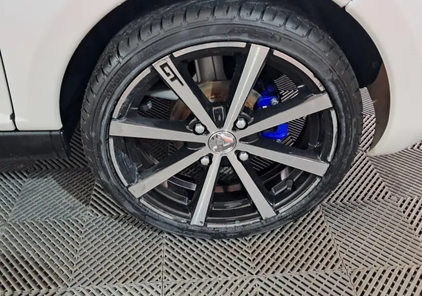 Gros plan sur la roue avant droite de l'AIXAM AMBITION 0.5 CITY COUPE GTI blanche avec étrier de frein bleu visible.