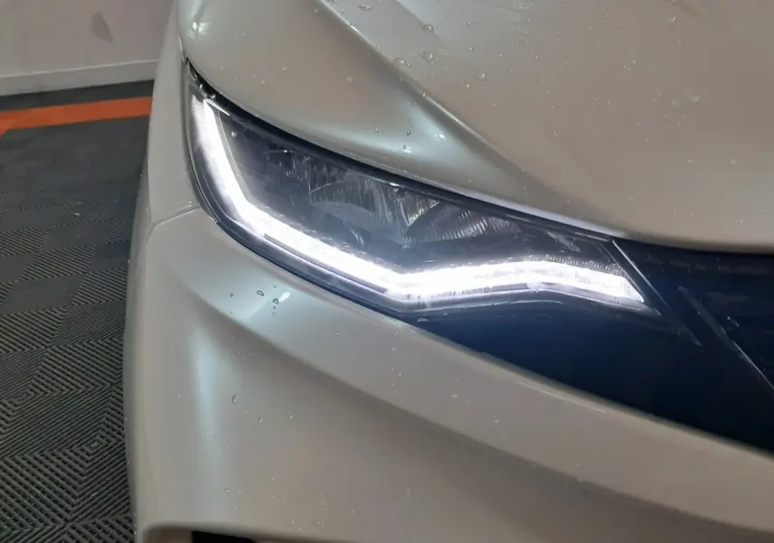 Gros plan sur le phare avant gauche blanc de l'AIXAM AMBITION 0.5 CITY COUPE GTI 2026 avec éclairage LED distinctif.