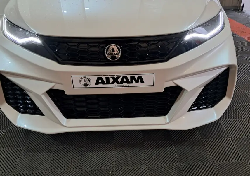 Vue frontale rapprochée de l'AIXAM AMBITION 0.5 CITY COUPE GTI blanche avec calandre noire et phares LED allumés.